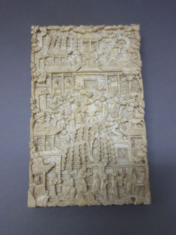 A Canton ivory rectangular card case, late 19th century, profusely carved with figures amongst pavilions and trees, 10.75cm. high.