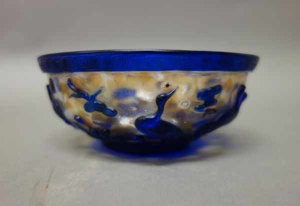 A Chinese overlay glass bowl, the clear glass with internal brown and white splashes, overlaid in blue with birds and lotus below a key pattern border