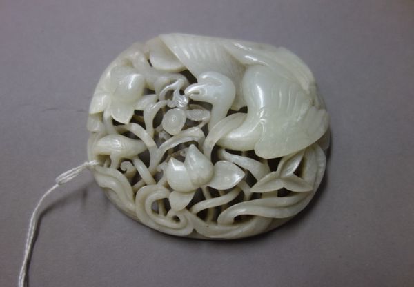 A Chinese white jade pierced plaque, carved with two birds amongst lotus, 10cm. wide.  Illustrated