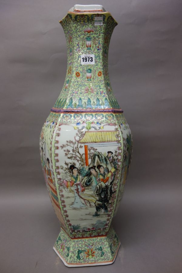 A tall Chinese famille-rose vase, 20th century, of hexagonal form, painted with panels of young women in landscapes against a lime green ground filled