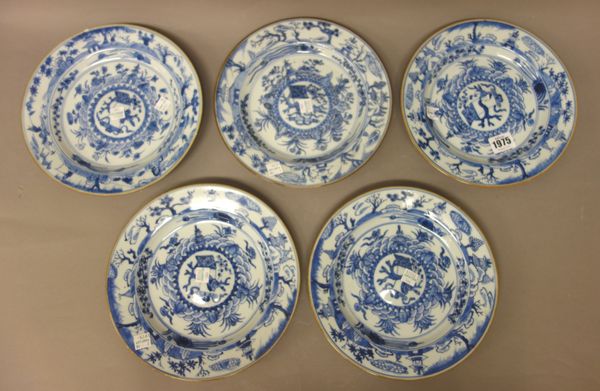 Five Chinese blue and white plates, Kangxi, each with a raised central panel enclosing a scroll, vase and prunus, inside a border painted with pavilio