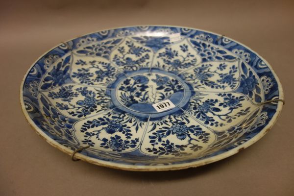 A Chinese blue and white dish, Kangxi, painted with a central panel of flowers inside barbed edged radiating flower panels, (a.f), 38.5cm. diameter.