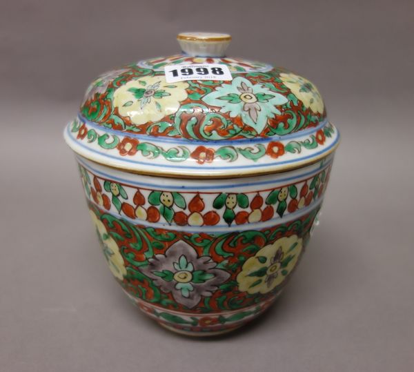 A Chinese wucai jar and cover, 19th century or earlier, painted with flower medallions against an iron-red ground with green foliage, 18cm. high; also