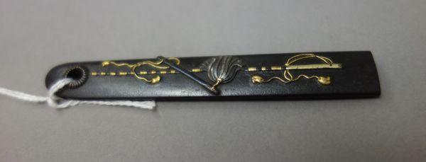 A Japanese iron kosuka, Edo period, 19th century, depicting military attributes in iroe-takazogan, signed, 9.8cm.length.  Illustrated