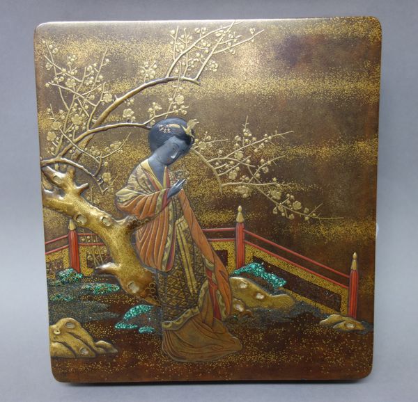 A Japanese lacquer suzuribako (writing box), Meiji period, of rounded square form, decorated with a woman leaning against a flowering plum tree, the i