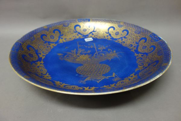 A Chinese powder-blue ground charger, blue Kangxi seal mark, but probably 19th century, finely gilt in the centre with a basket of flowers and fruit,