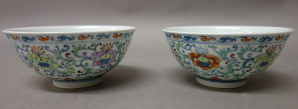 A pair of Chinese doucai bowls, Yongzheng six character marks but later, each painted on the exterior with flowers and tendrils above a ruyi head bord