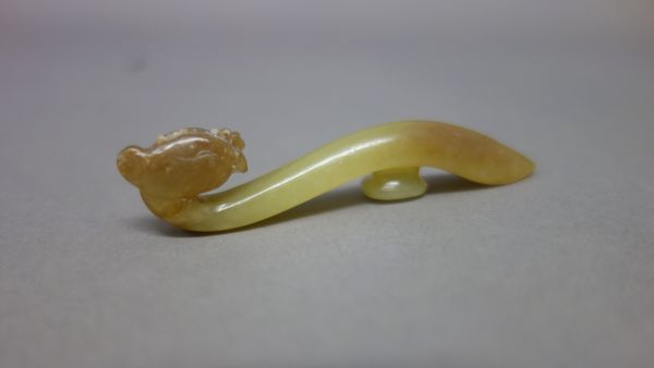 A Chinese yellow jade `phoenix' belthook, Tang Dynasty, finely carved with a phoenix head forming the end of the hook, the shaft sharply curved, the s