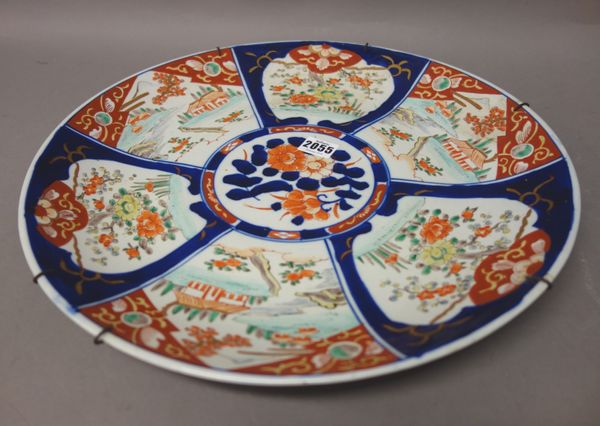 A Japanese Imari dish, Meiji period, painted with a central flower panel inside radiating panels enclosing landscapes and flowering shrubs, 40cm. diam