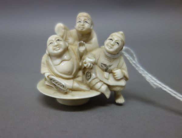 A Japanese ivory netsuke, early 20th century, carved with three figures including Hotei and Daikoku, signed, 4.5cm. high; also an ivory netsuke of a t