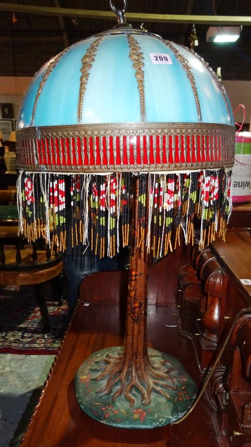 In the manner of Tiffany, a large 20th century table lamp with naturalistic cast iron base formed as a rooting tree, with a blue glass and metal mount