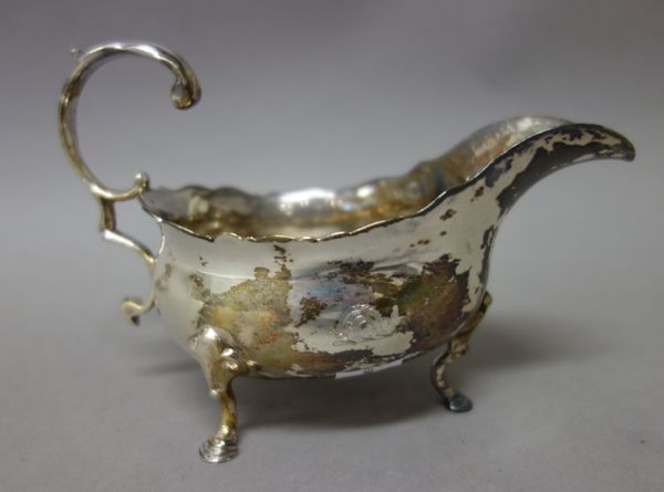 A George III silver sauceboat, with a scrolling handle, shaped rim and raised on three pad feet, London 1765, weight 186 gms.