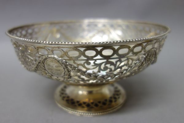 A silver bowl of circular form, with pierced and cast scroll and foliate swag decoration, within a beaded rim, raised on a pierced circular foot, havi