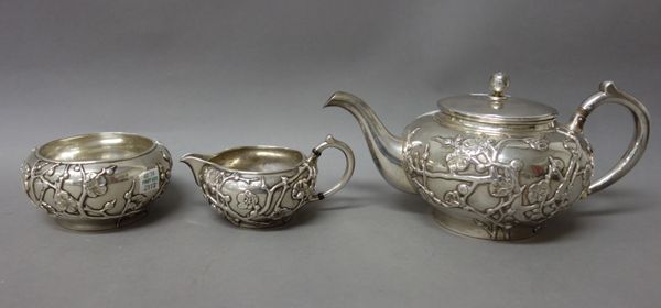 A three piece tea set, comprising; a teapot, a sugar bowl and a milk jug, each piece of circular form,  the bodies decorated with blossom, the marks t