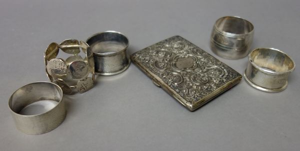 Four silver napkin rings, in a variety of designs, a napkin ring made from Spanish American coins and a rectangular aide-memoire, with floral, scroll