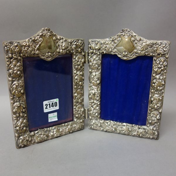 A late Victorian silver mounted shaped rectangular double photograph frame, with floral and foliate scroll embossed decoration, Birmingham 1898, one g