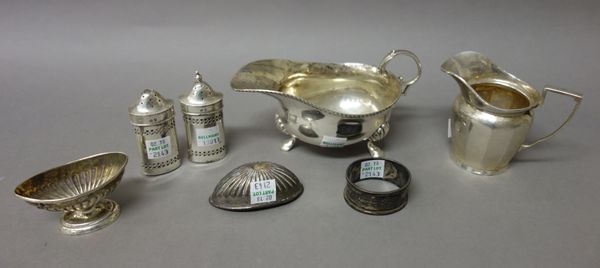 Silver, comprising; a sauce boat decorated with a gadrooned rim, raised on three feet, London 1867, a cream jug, Birmingham 1918, a pair of oval peppe