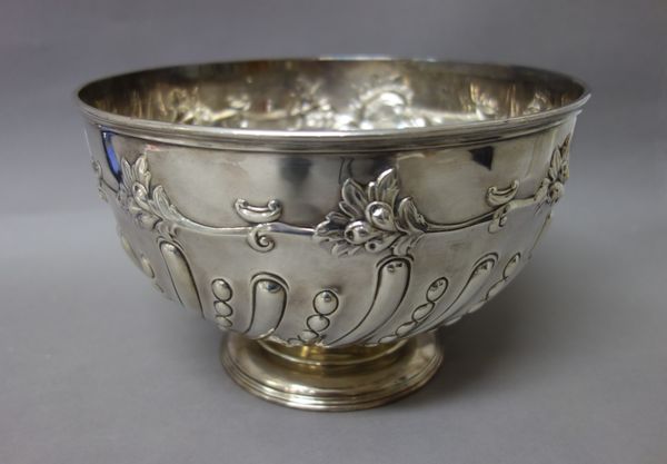 A silver rose bowl of circular form, the body embossed with semi spiral fluted bands, below foliate embossed scrolls, raised on a circular foot, diame