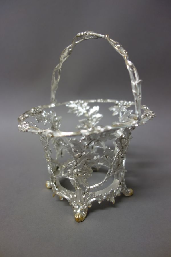 A Victorian silver sugar basket, modelled as oak leaf sprays with acorns and raised on four scrolling feet, with a cast swingover handle, having a cen