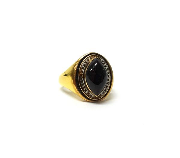 A gold, carbuncle garnet and white enamelled ring, collet set with the oval carbuncle garnet, within a white enamelled border, detailed 22, ring size