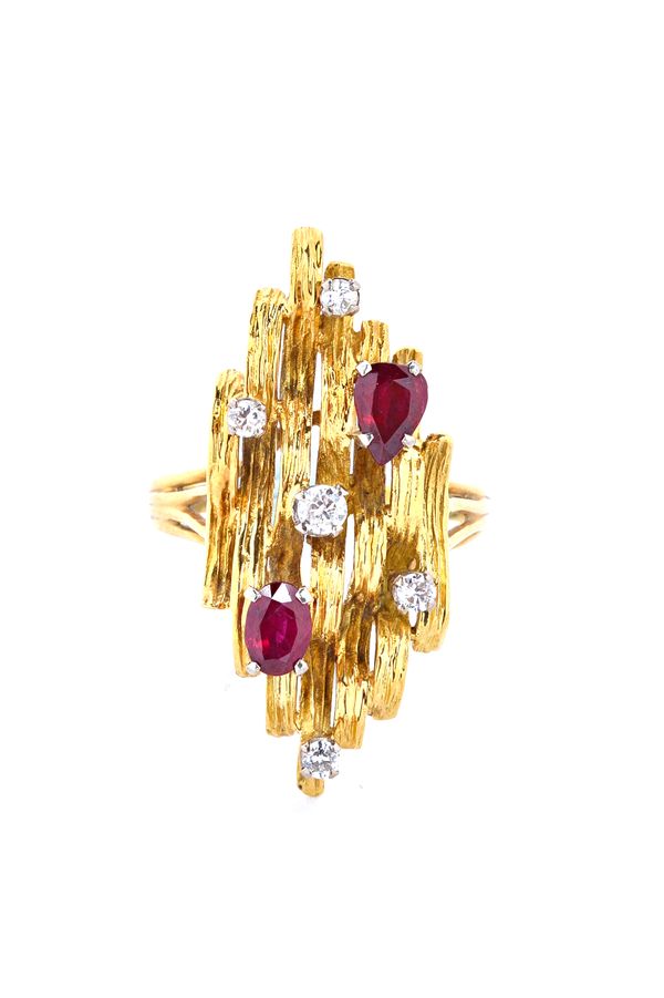 An 18ct gold, diamond and ruby seven stone ring, claw set with five circuclar cut diamonds, a pear shaped ruby and with an oval cut ruby, in an abstra