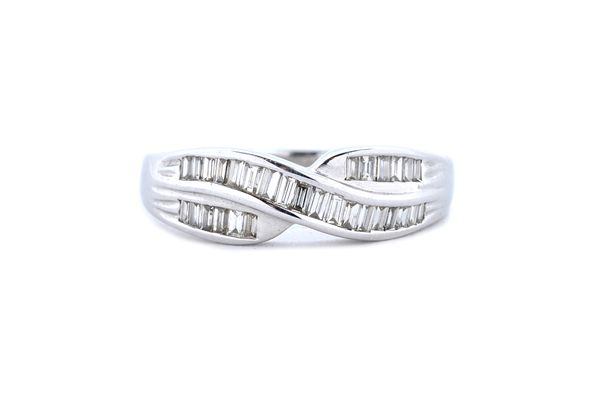 A 9 ct gold and diamond set ring, mounted with rows of baguette diamonds in a twist over design, detailed 9 K, ring size O.   Illustrated