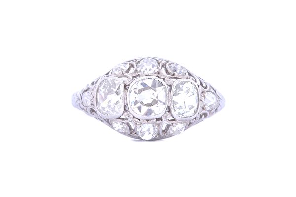 A white gold and diamond ring, collet set with the three principle cushion shaped diamonds to the centre, within a pierced openwork surround, further