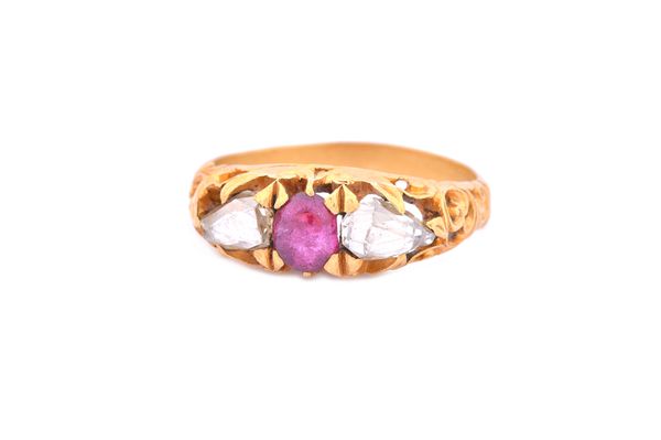 A gold, ruby and diamond set three stone ring, mounted with the oval cabochon ruby to the centre between two rose cut diamonds, the mount with scroll