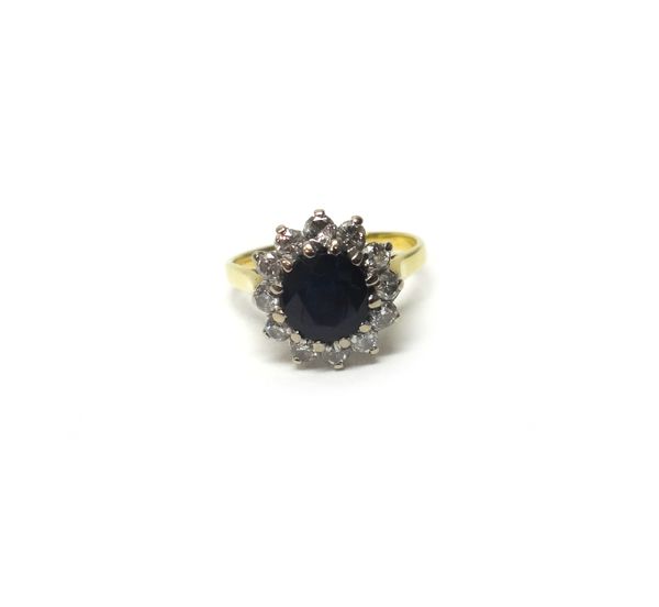 A gold, sapphire and diamond set cluster ring, claw set with the oval cut sapphire at the centre, in a surround of circular cut diamonds, ring size J