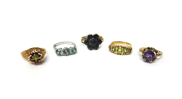 A 9ct white gold and blue zircon set three stone ring, a Bohemian garnet set seven stone cluster ring, a gold and peridot set five stone ring, detaile