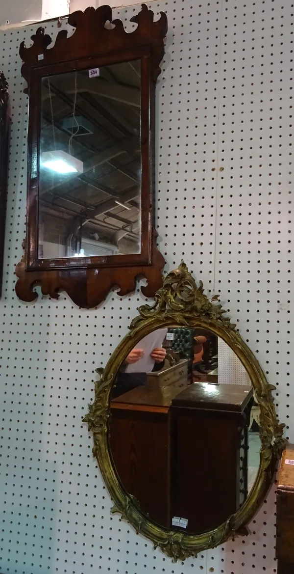 A George II style walnut framed fret cut mirror, 46cm wide x 96cm high and a Rococo style oval gilt framed wall mirror, 52cm wide x 73cm high, (2).  A