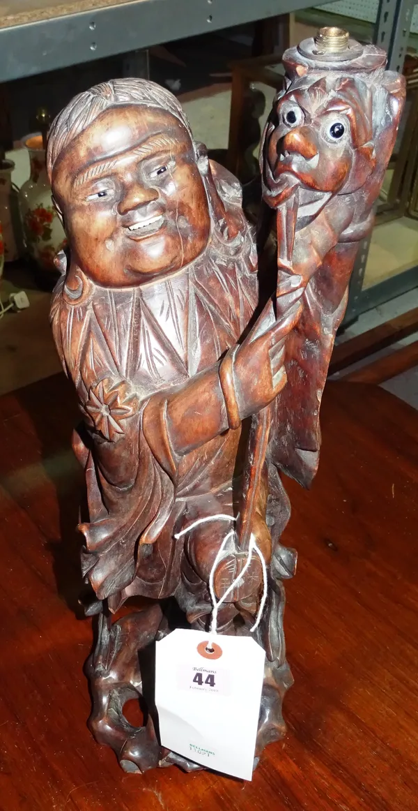 A Chinese hardwood figure, early 20th century, carved as a smiling man holding aloft a mythical creature, adapted as a lamp, 44cm. high  F3