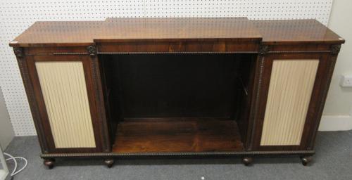 A Regency rosewood side cabinet with open shelves flanked by pleated silk panel doors, on turned feet, 185cm wide x 96cm high x 38cm deep.  K7