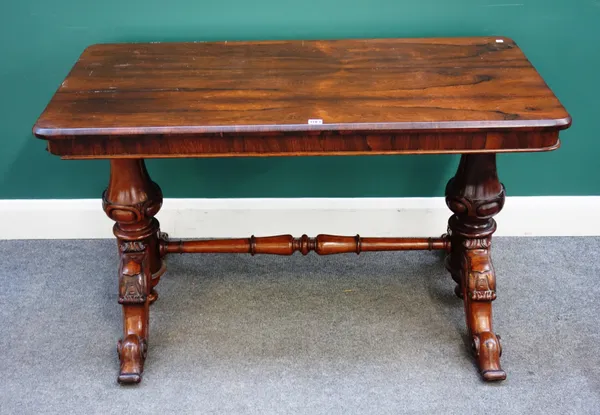 A Victorian rosewood centre table with round rectangular top on pair of carved columns and four scroll supports, 123cm wide x 73cm high x 61cm deep.