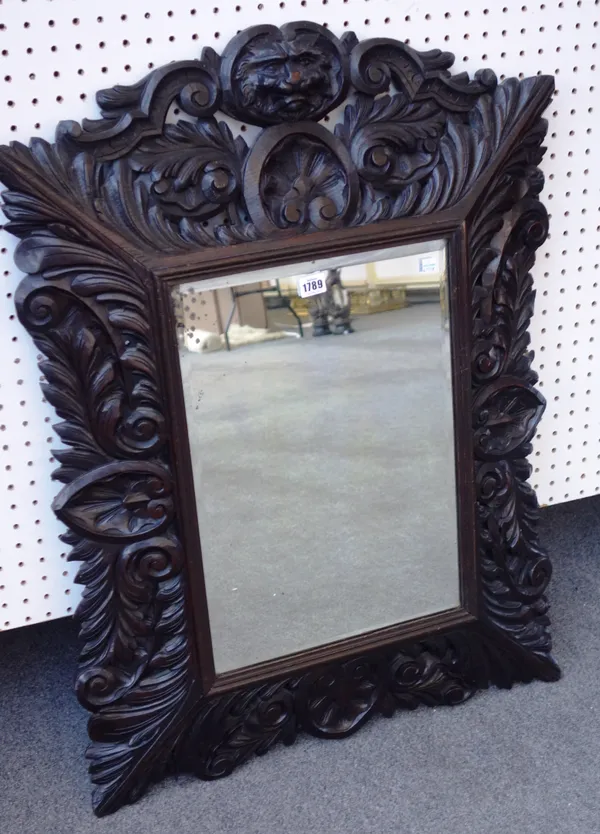 A late 19th century Dutch wall mirror, the carved oak swept frame with lion face mask, 67cm wide x 91cm high.  A6