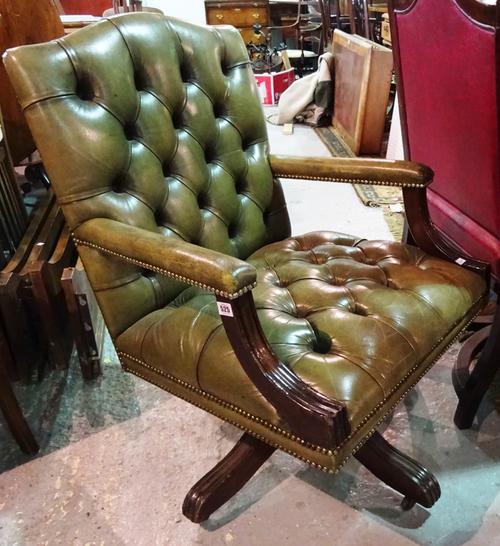 An early 20th century mahogany office swivel open armchair, with button back green leather upholstery.  B7