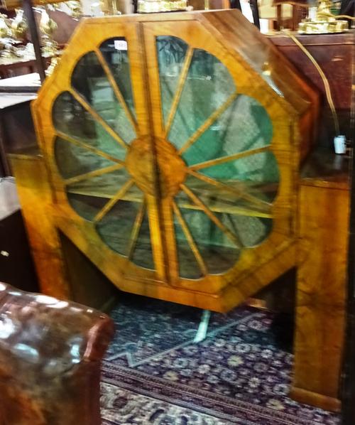 An Art Deco walnut display cabinet with octagonal centre section and petal glazed doors, flanked by narrow bookcase supports, 118cm wide x 121cm high.