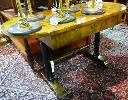 A Biedermeier style walnut oval top side with ebonised column on trestle supports, 130cm wide x 70cm high.  F8