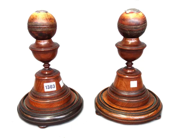 A pair of cricket trophies, late 19th century, the two cricket balls with silver presentation plaques, on turned mahogany stands, 28cm high, (2).Reput
