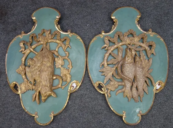 A pair of 19th century gilt and later painted carved wood wall appliques probably German, each relief carved with hanging game, against a later green