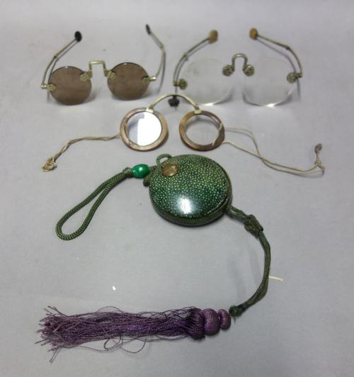 A pair of Chinese folding spectacles, 19th century, horn rims with metal and string contained in a circular shagreen box and cover and two further pai