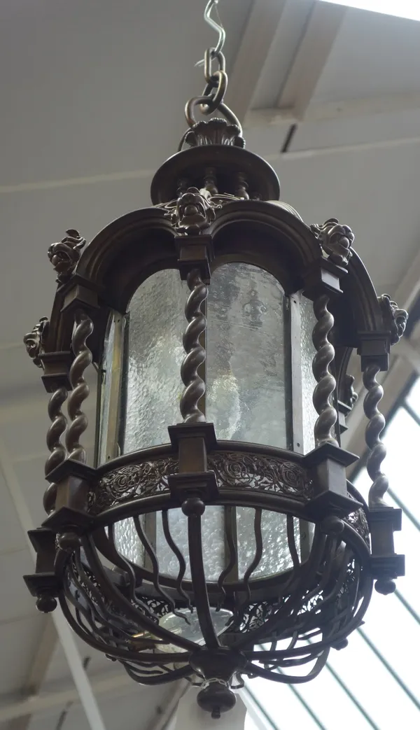 A pair of modern bronze lanterns, each with domed and pillared final over a barley twist frame enclosing an octagonal glass shade and three light fitm