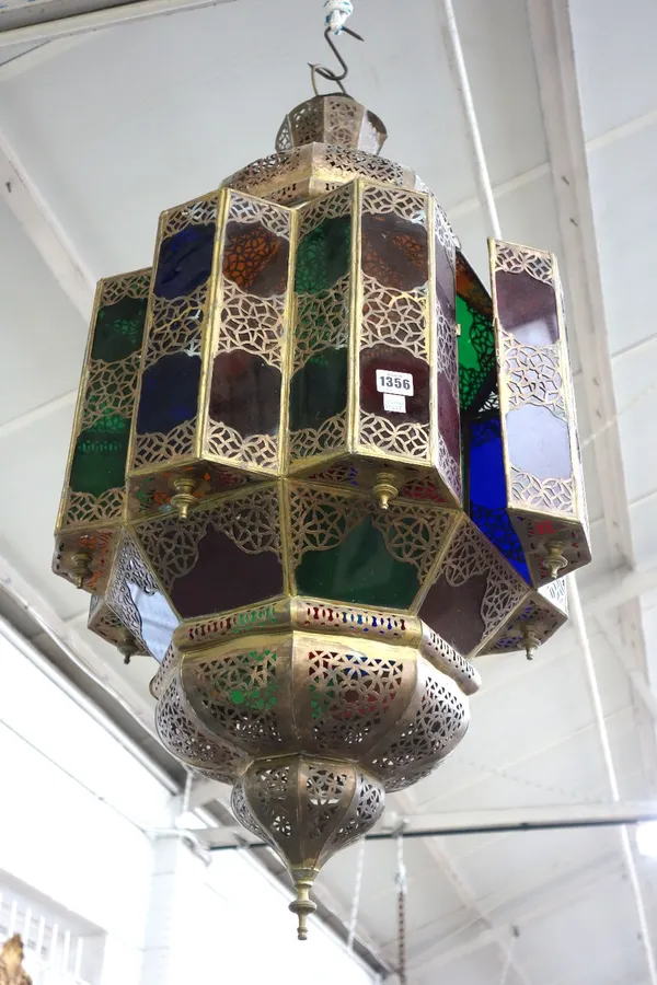 A Middle Eastern sheet metal and coloured glass hanging lantern, late 20th century, of pierced octagonal form with domed ends. 90cm high.