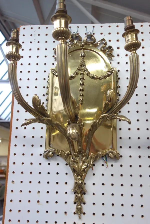 A set of four Louis XVI style gilt brass three branch wall lights, modern, with ribbon and foliate swag embellishments against a domed rectangular bac