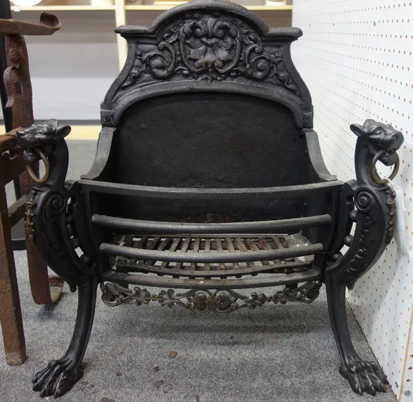 A cast iron and brass mounted three bar fire grate, circa 1900, with shaped foliate back and lion ring handle supports on lion paw feet, 70cm high.