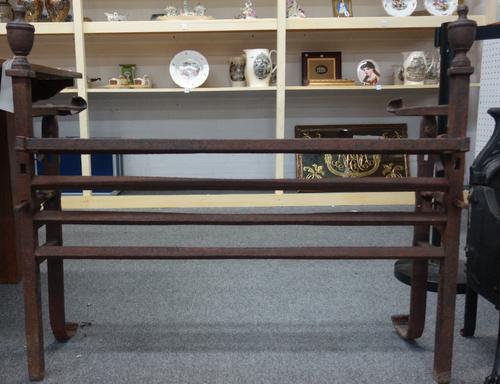 A cast iron fire grate stand, early 19th century, with four bar hanging rail, spit roast terminals and pot hangers, with twin Adams urn finials over t