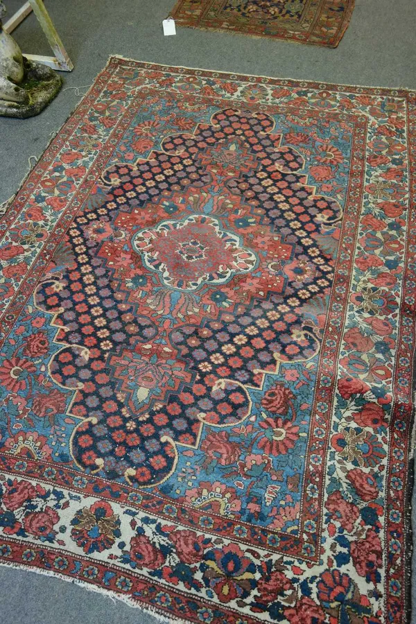 A Bakhtiari rug, Persian, the indigo field with a bold madder medallion, surrounded by rows of flowerheads, pale indigo spandrels, an ivory floral bor