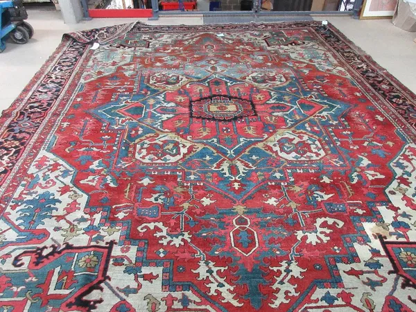 A Heriz carpet, early 20th century, the central stepped medallion on a red ground with white spandrels and tendrils within a blue main border, 318cm x