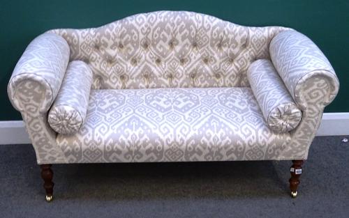 A modern small hump back sofa with roll over arms on turned supports, 140cm wide x 77cm high.