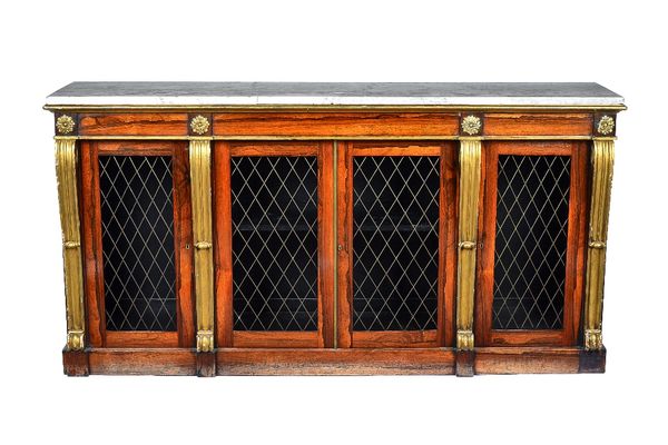 A William IV side cabinet In the manner of Marsh & Tatham, the marble top over four grille doors, divided by gilt scrolls, on a plinth base, 187cm wid